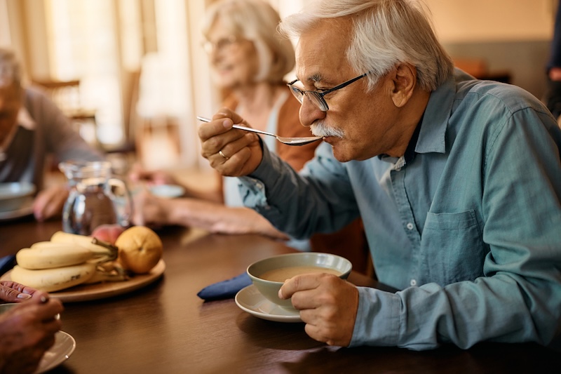 older man eating lower sodium soup with umami